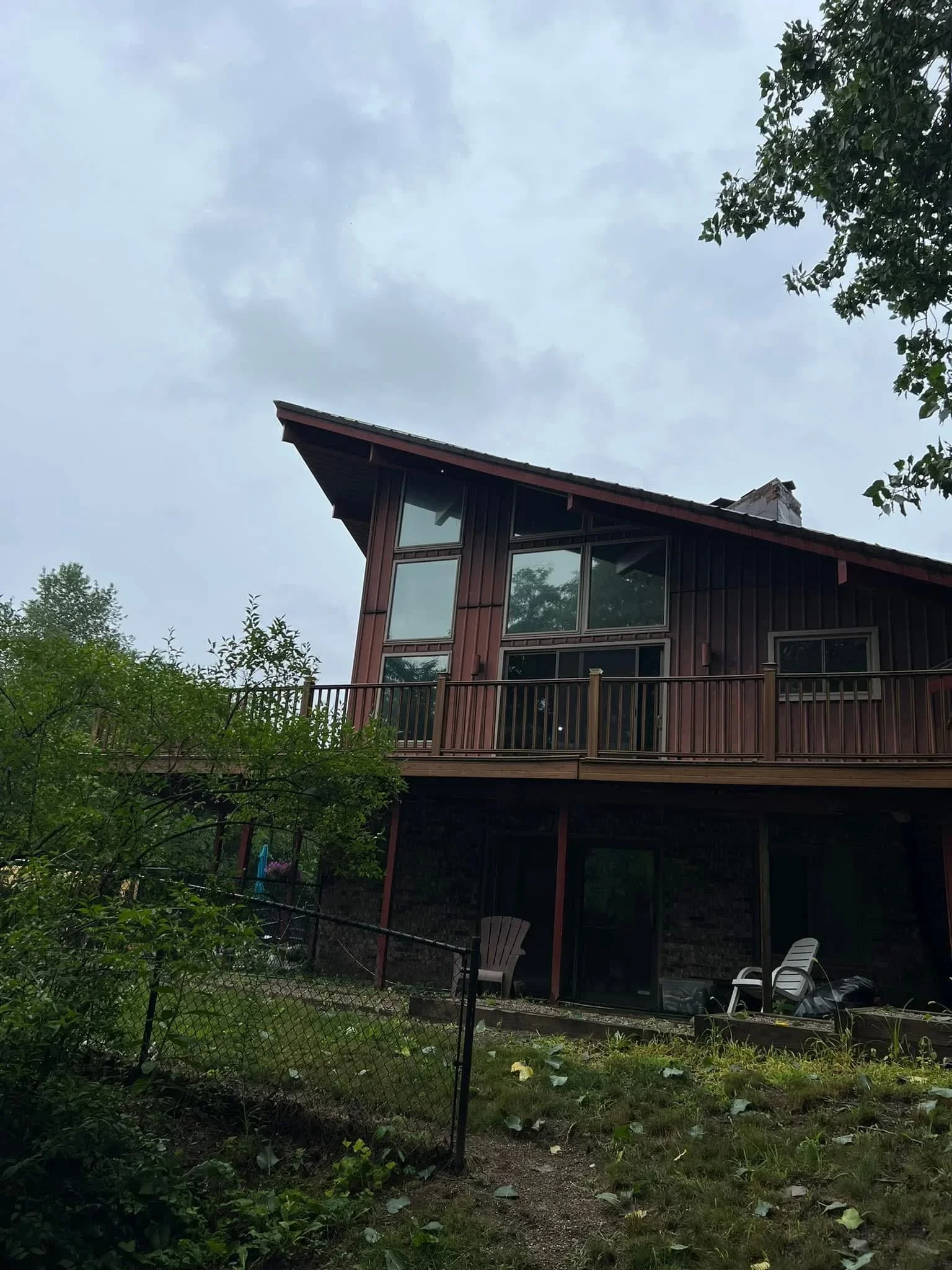 Dark-tinted windows on two-story residential home with metal railings and deck