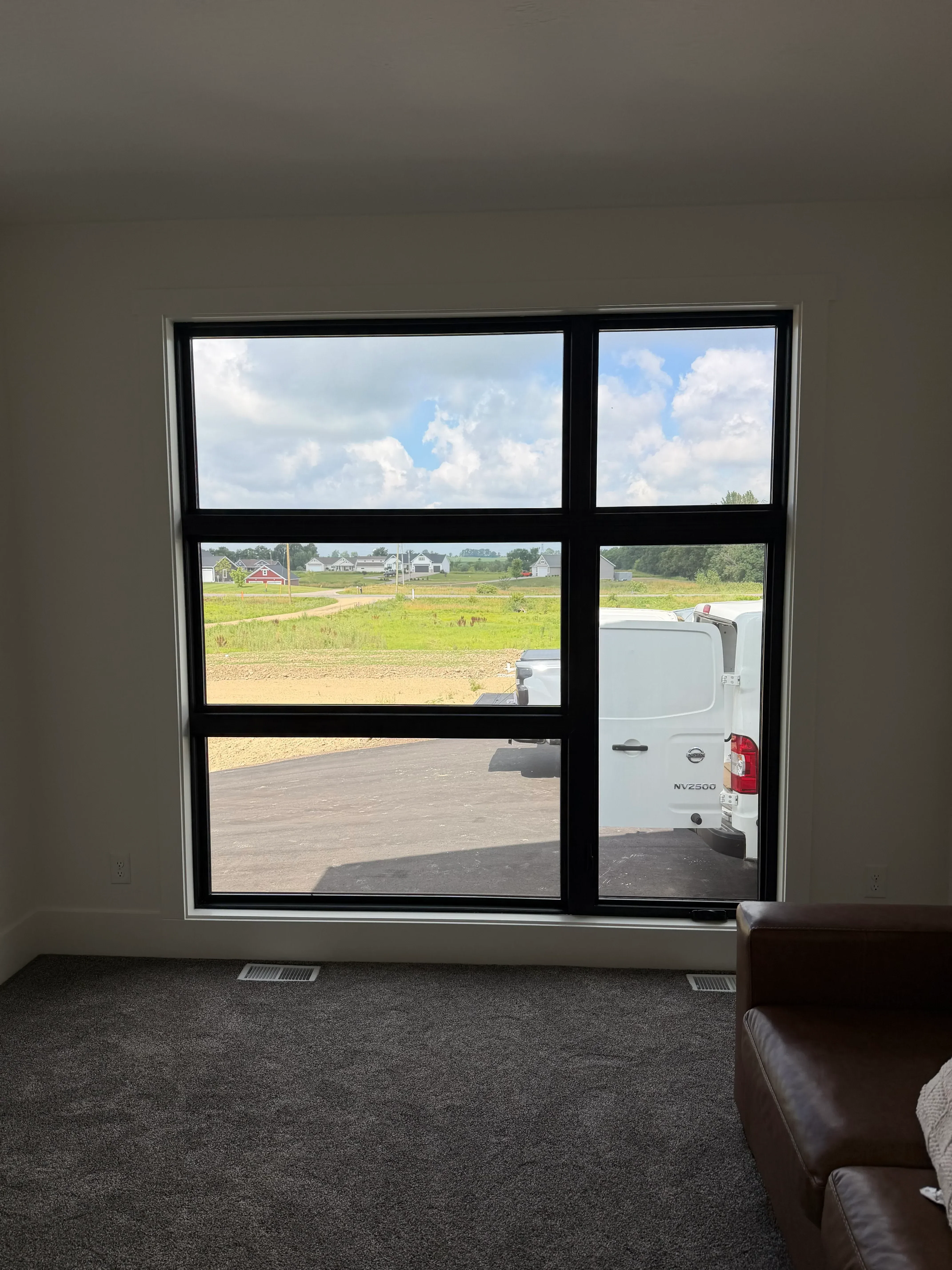 Black-framed five-pane window with clear glass panels installed in drywall opening