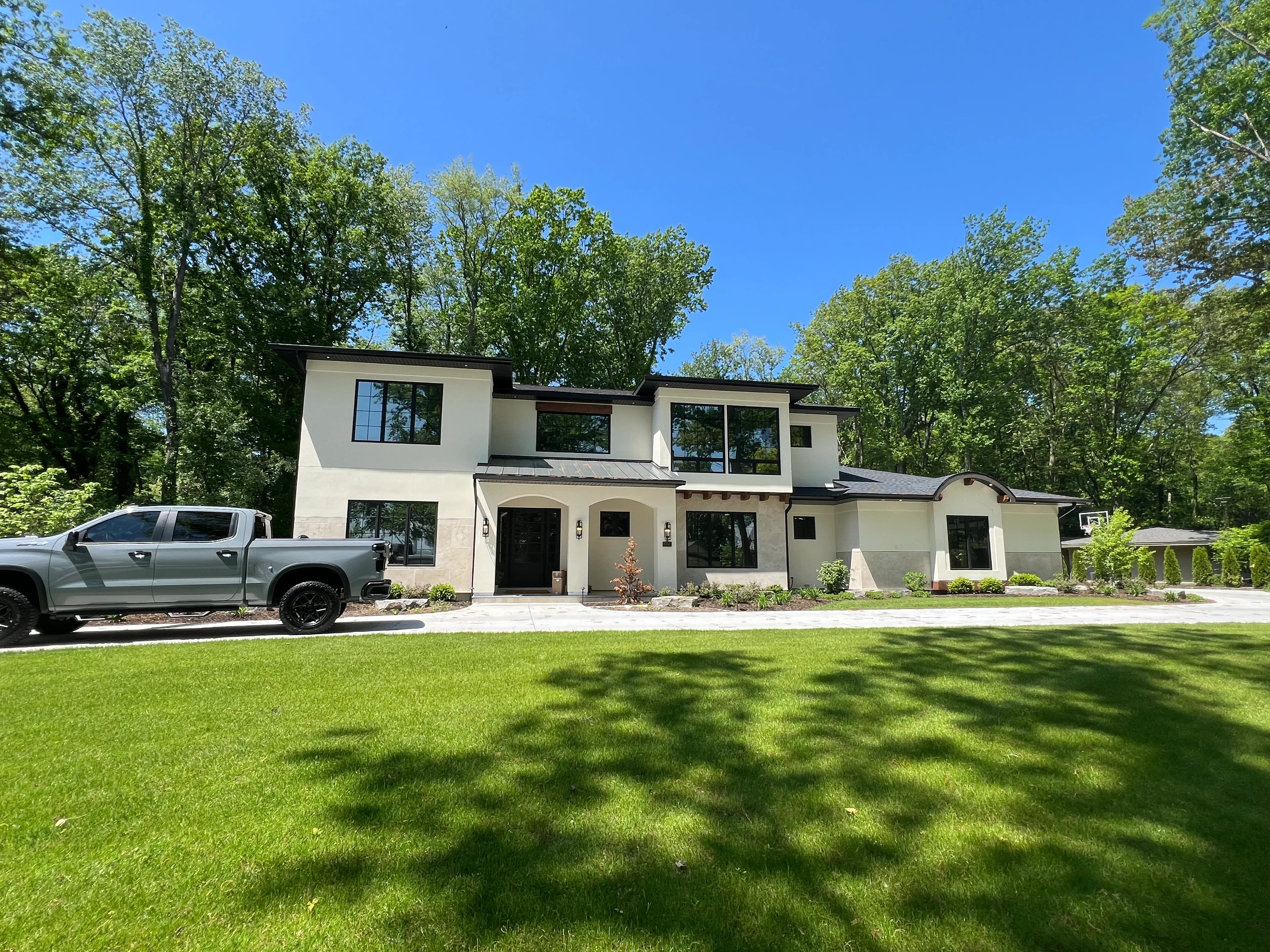 Modern home with black-framed windows and glass installations on white stucco facade