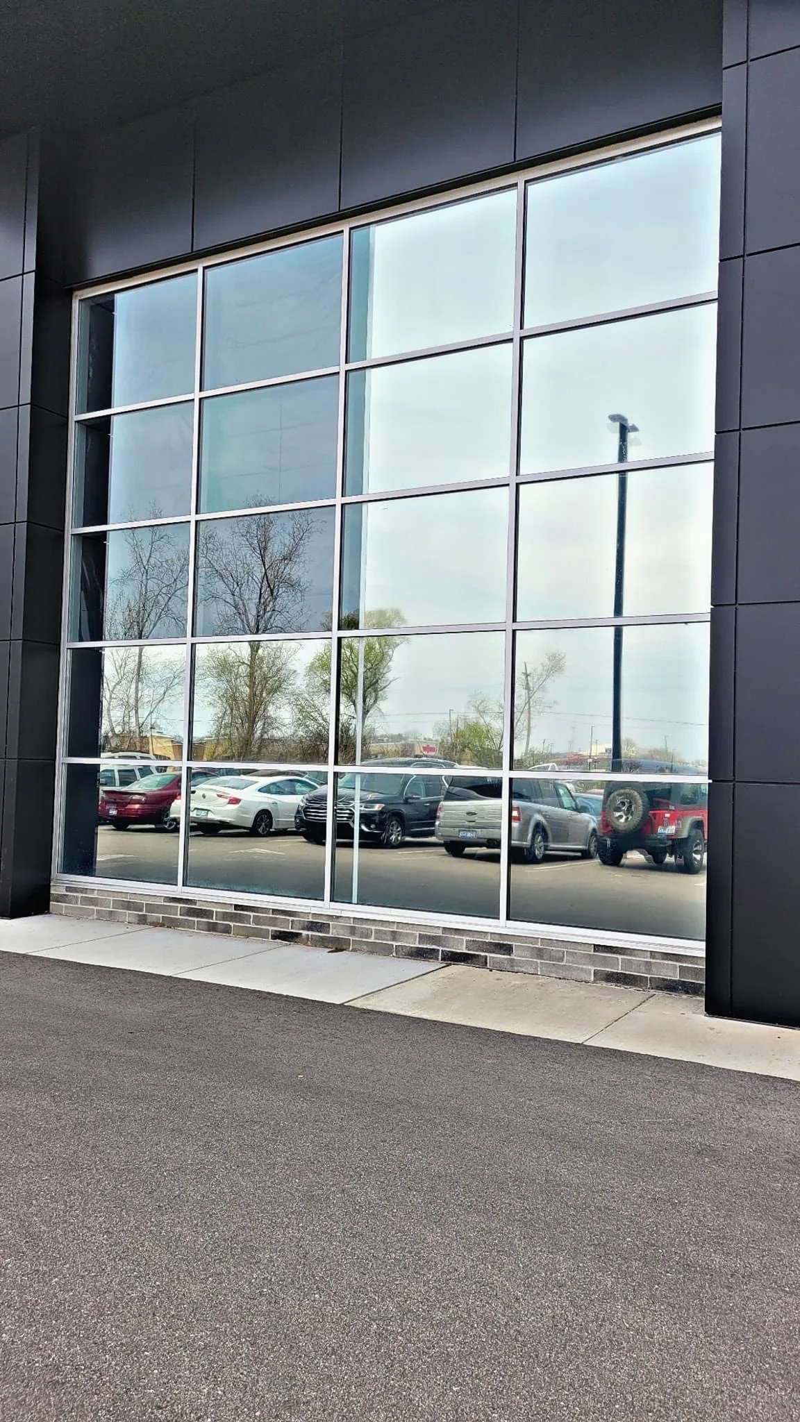 Commercial storefront with aluminum-framed grid windows and clear glass panes on dark facade