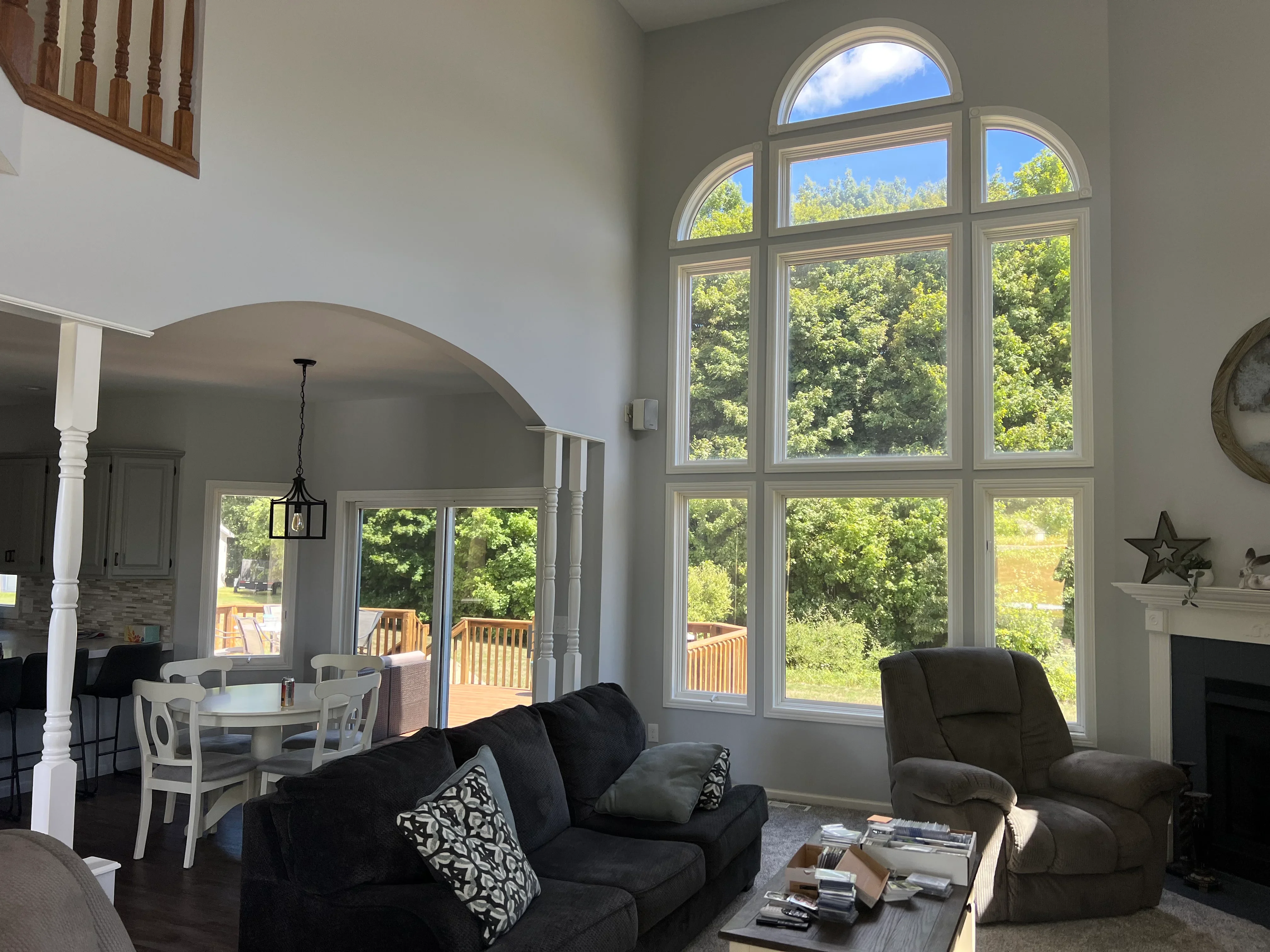 Large multi-pane arched window installation with white frames in residential living room