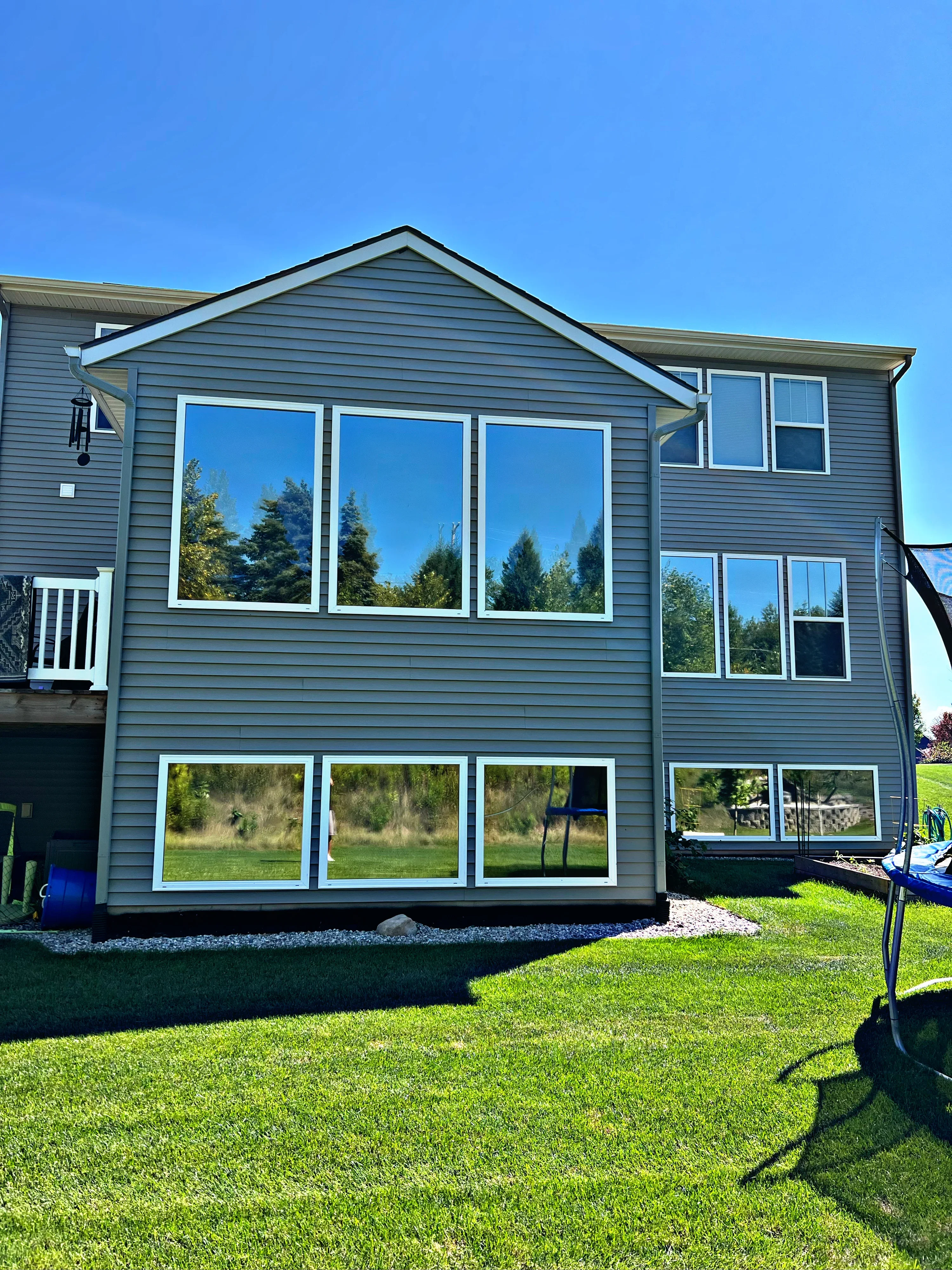 Gray vinyl-sided house with professionally tinted windows on upper and lower levels