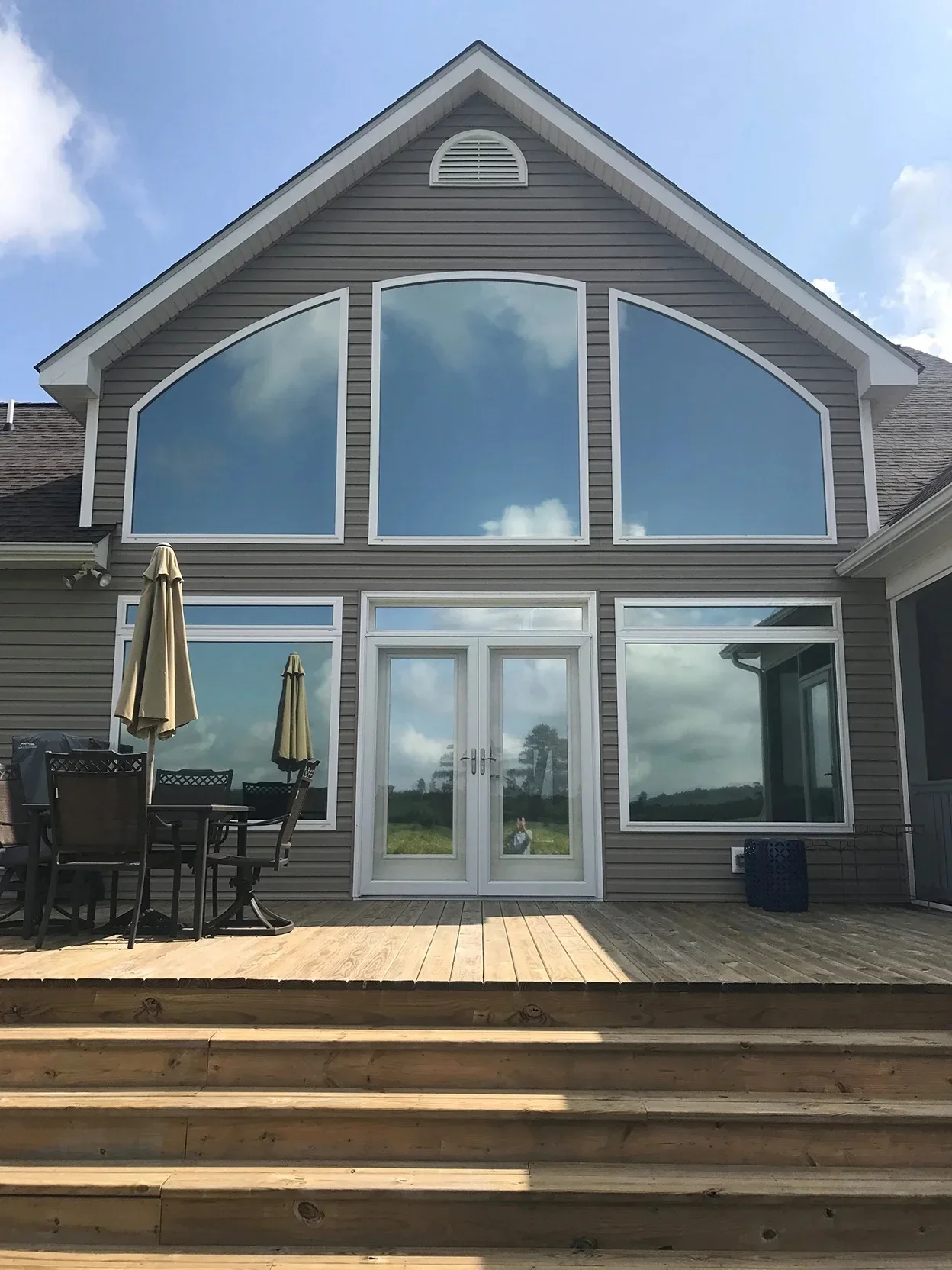 Large residential windows with professional tinting on gray siding home with white trim