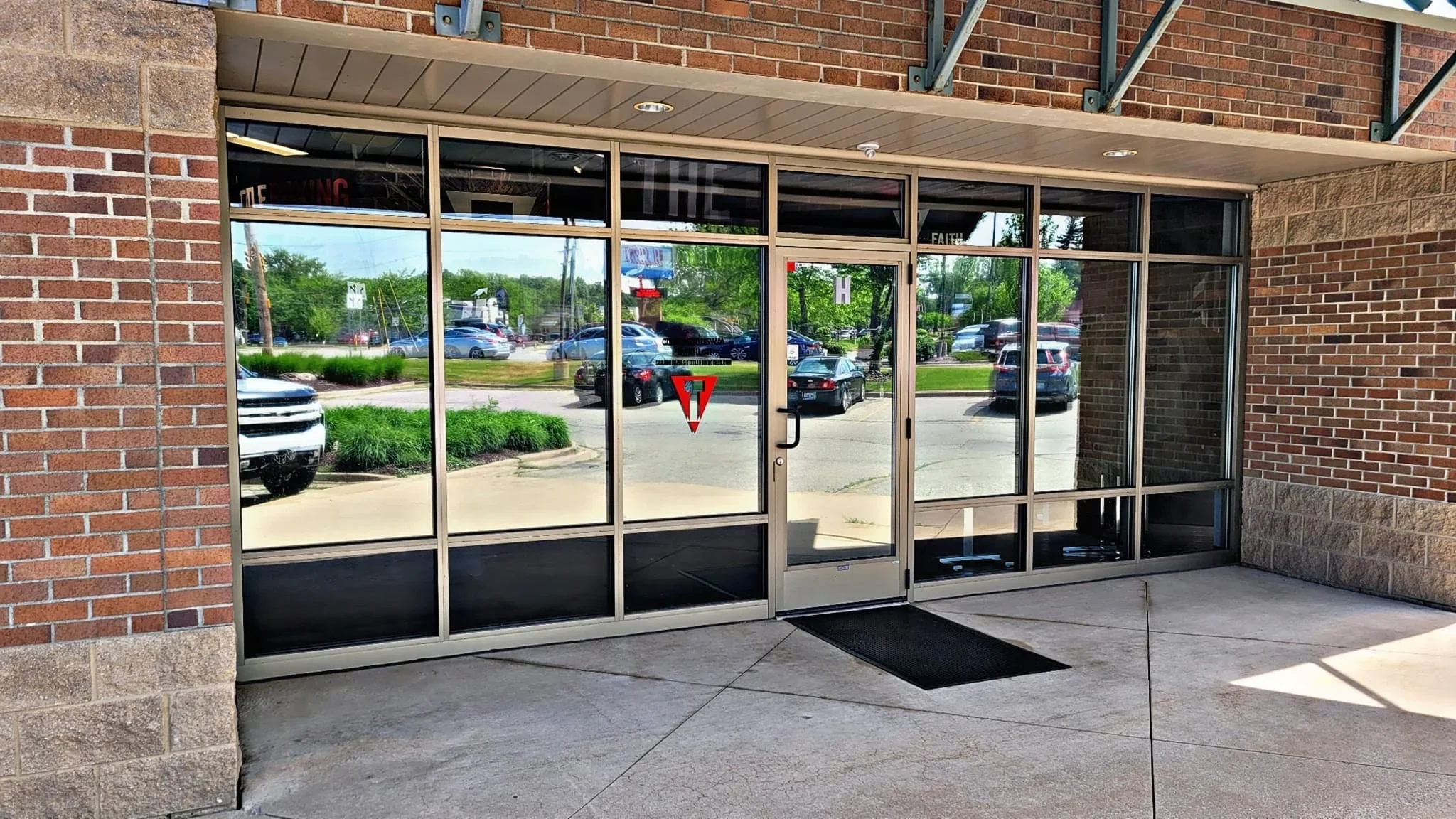 Commercial storefront with tinted glass panels and aluminum frame entrance on brick building