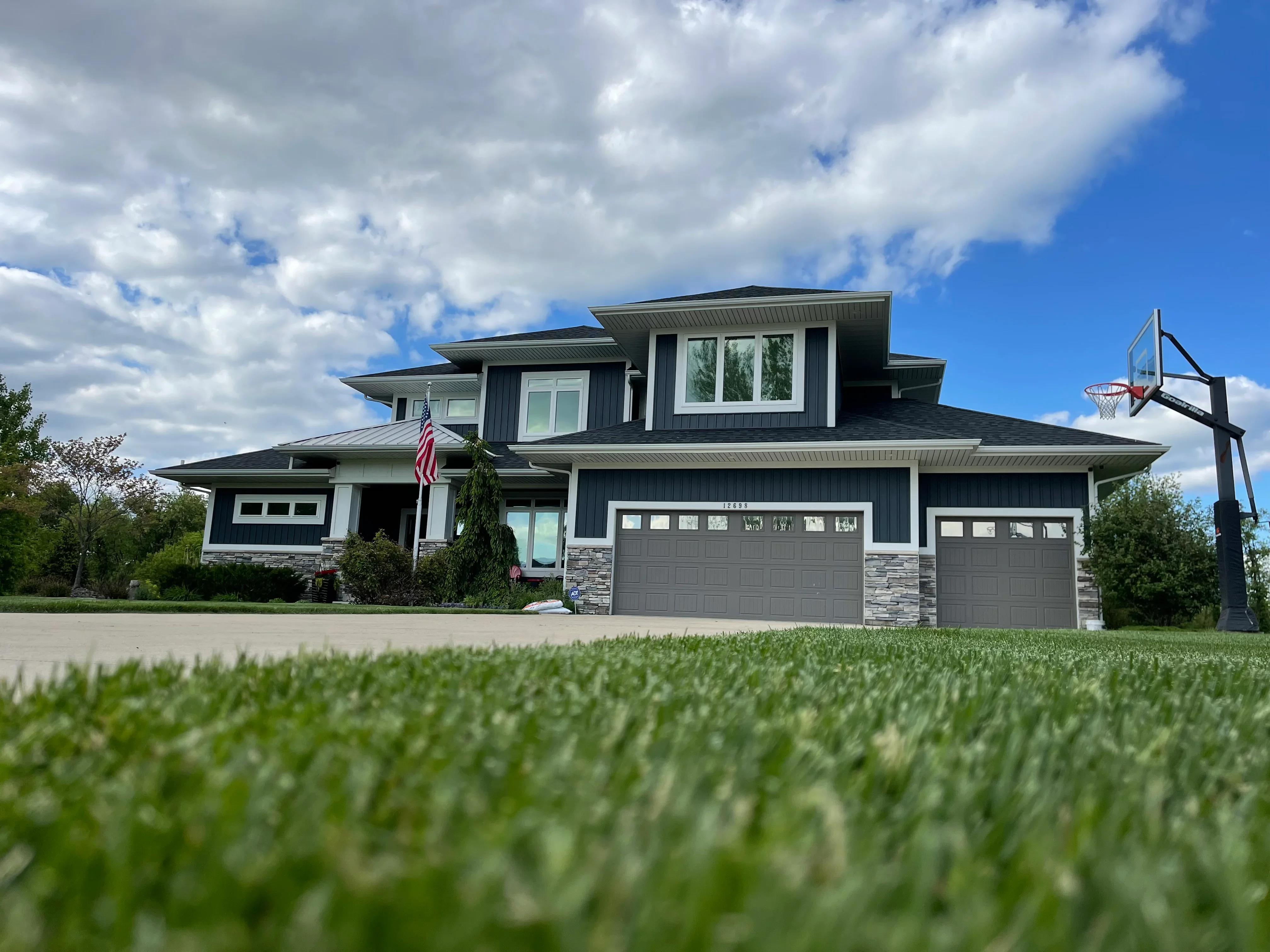 Modern two-story home with dark siding, stone accents, and professionally installed windows