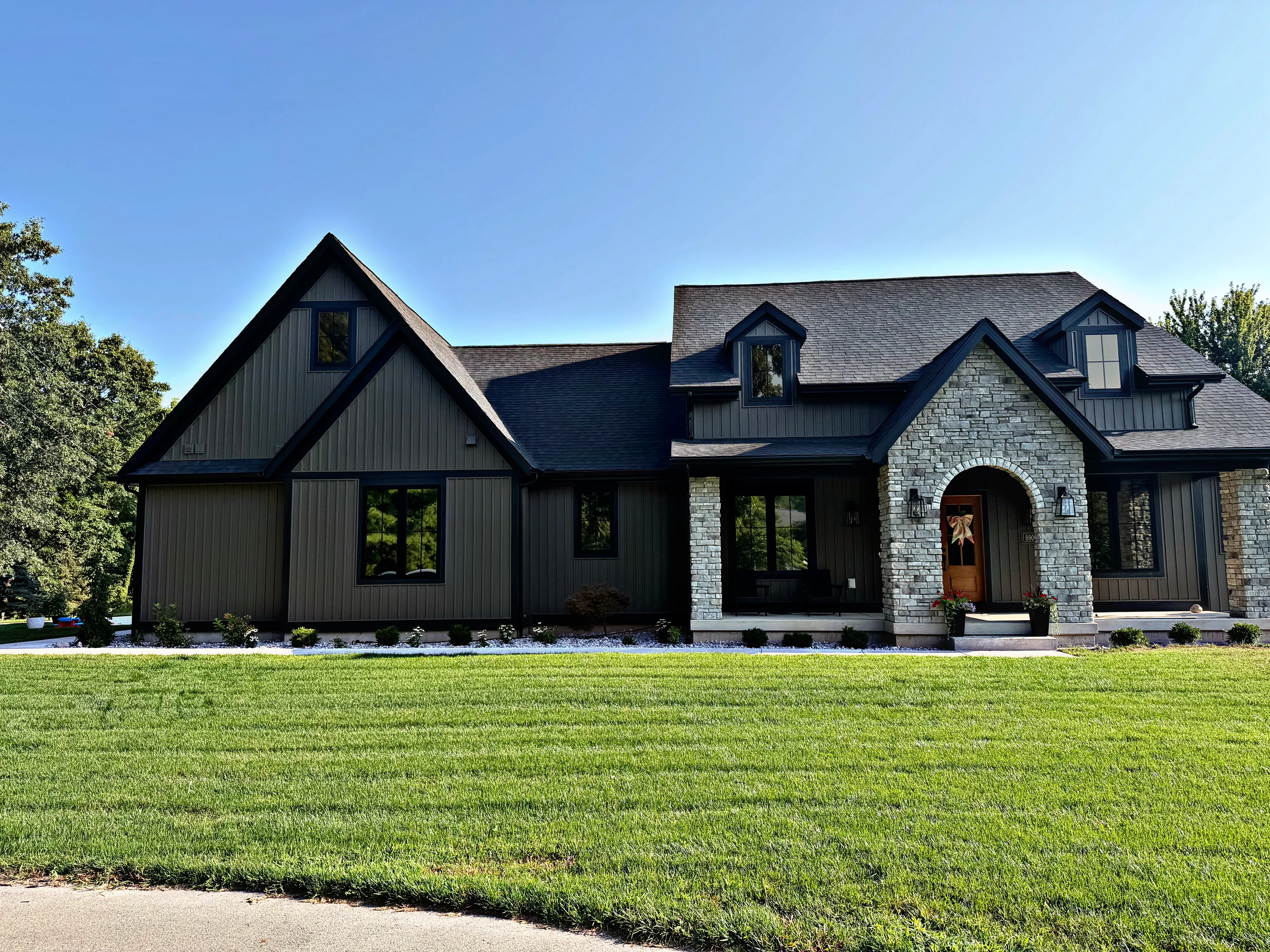 Black metal and stone home with professionally tinted windows and dark-framed glass installations