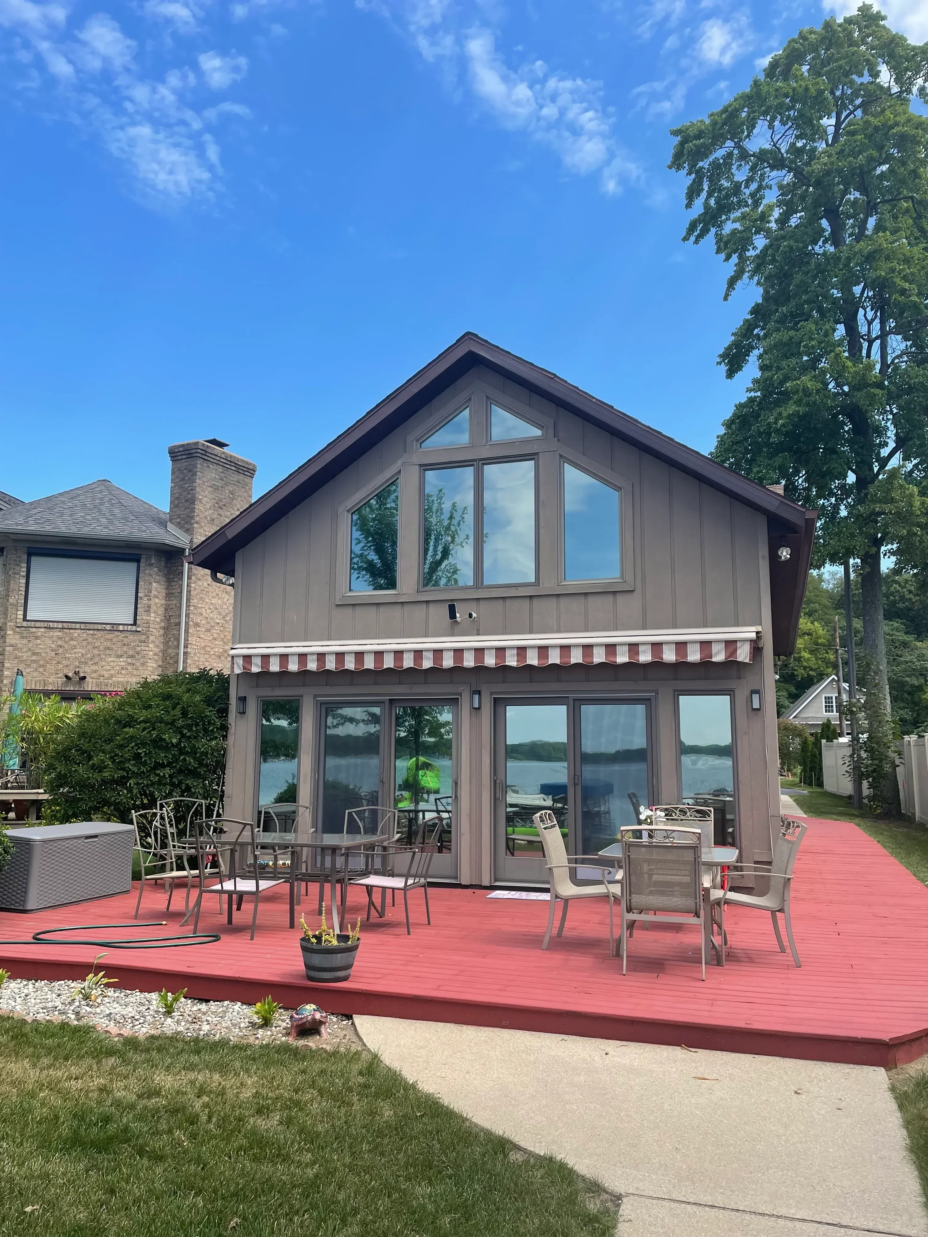 Residential home with professionally tinted windows on front facade, gray siding and brick chimney