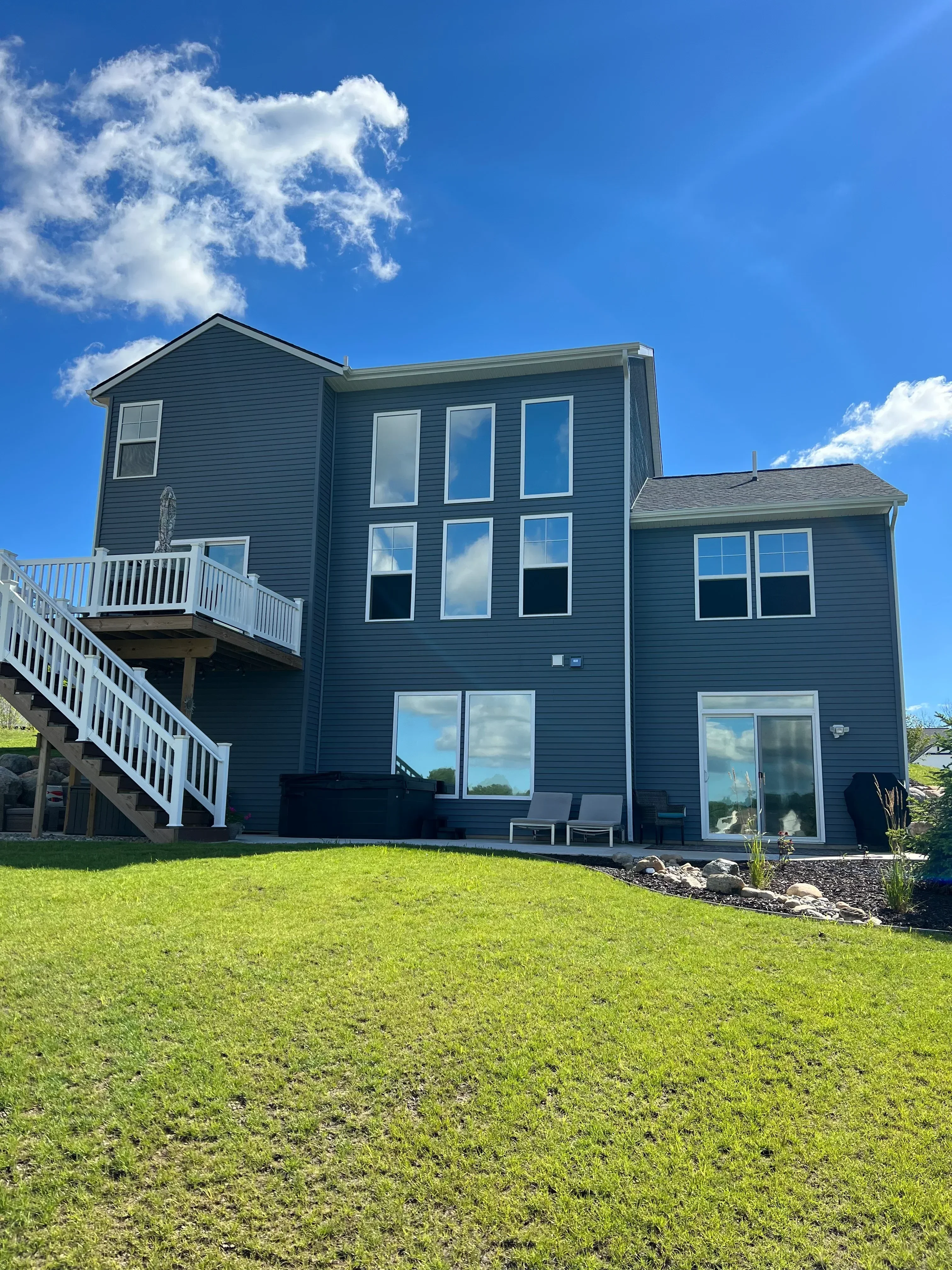 Dark metal-sided home with tinted windows on two-story residential structure