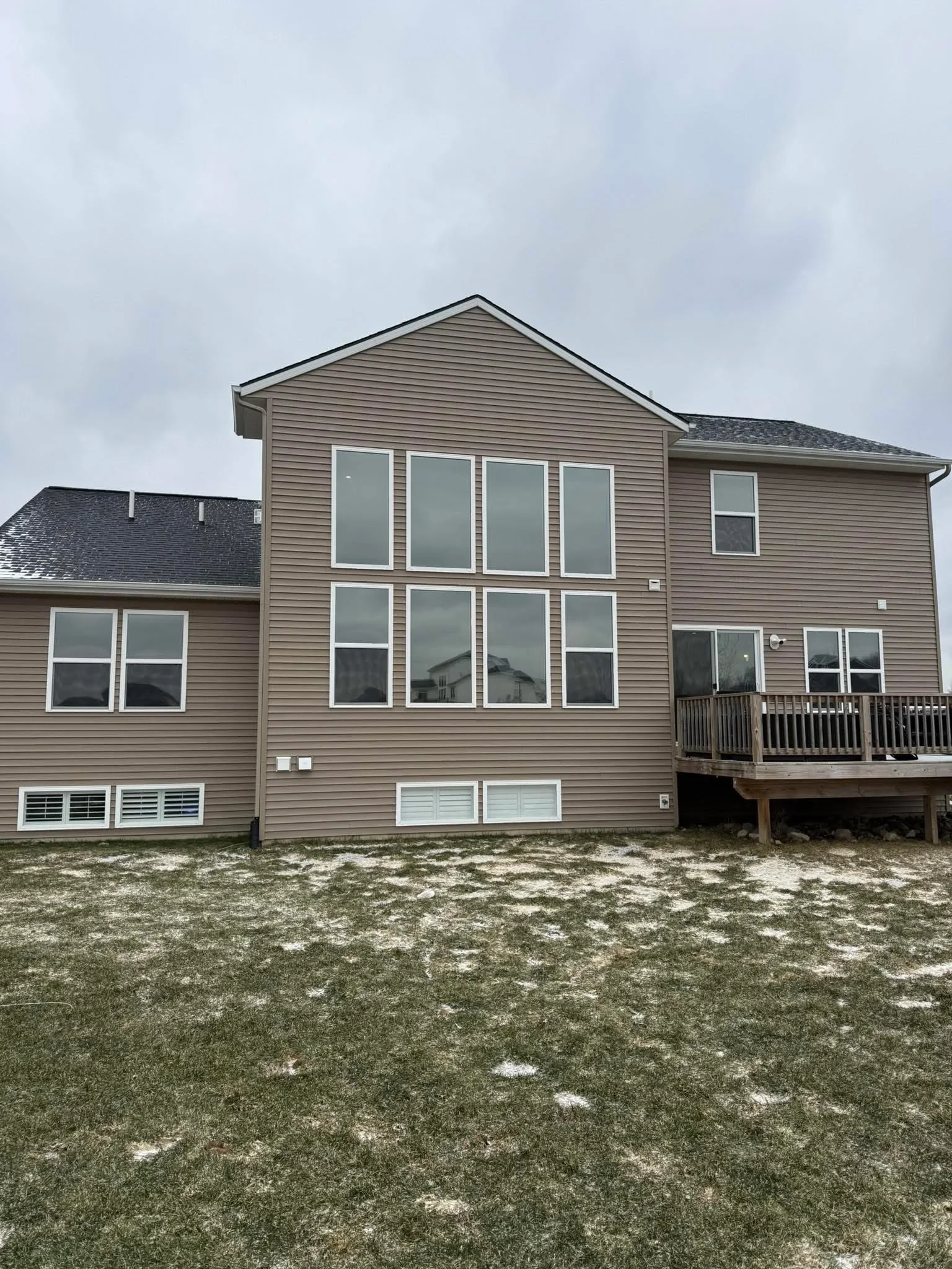 Vinyl-sided home with multiple tinted picture windows and residential window installation