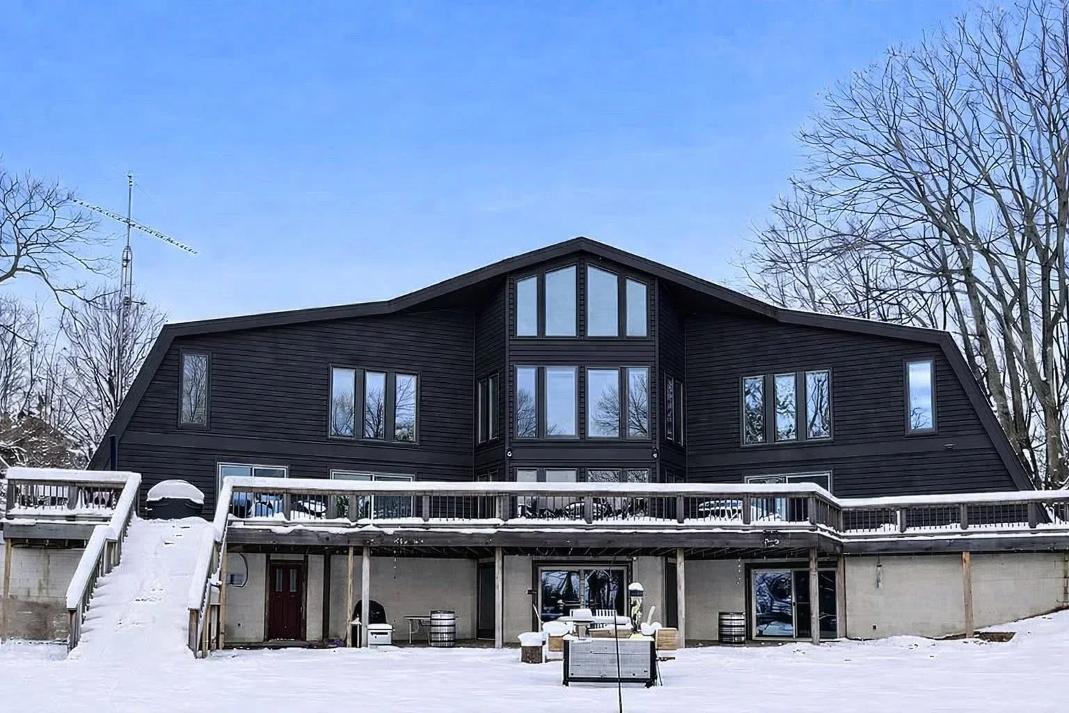 Black modern home with multiple large installed windows and arched transom window above entrance