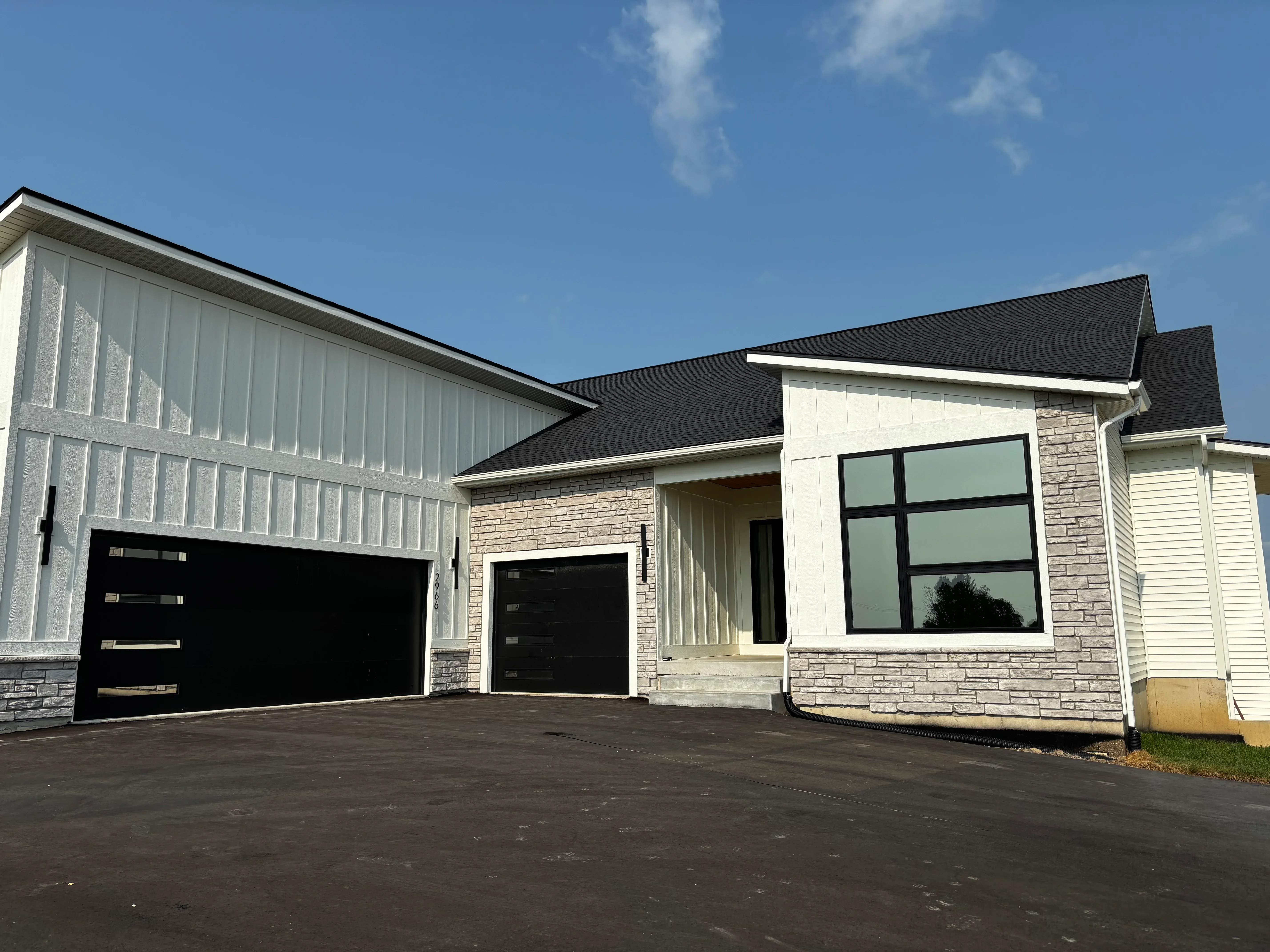 Tinted residential windows on stone and siding home with black-framed glass panels