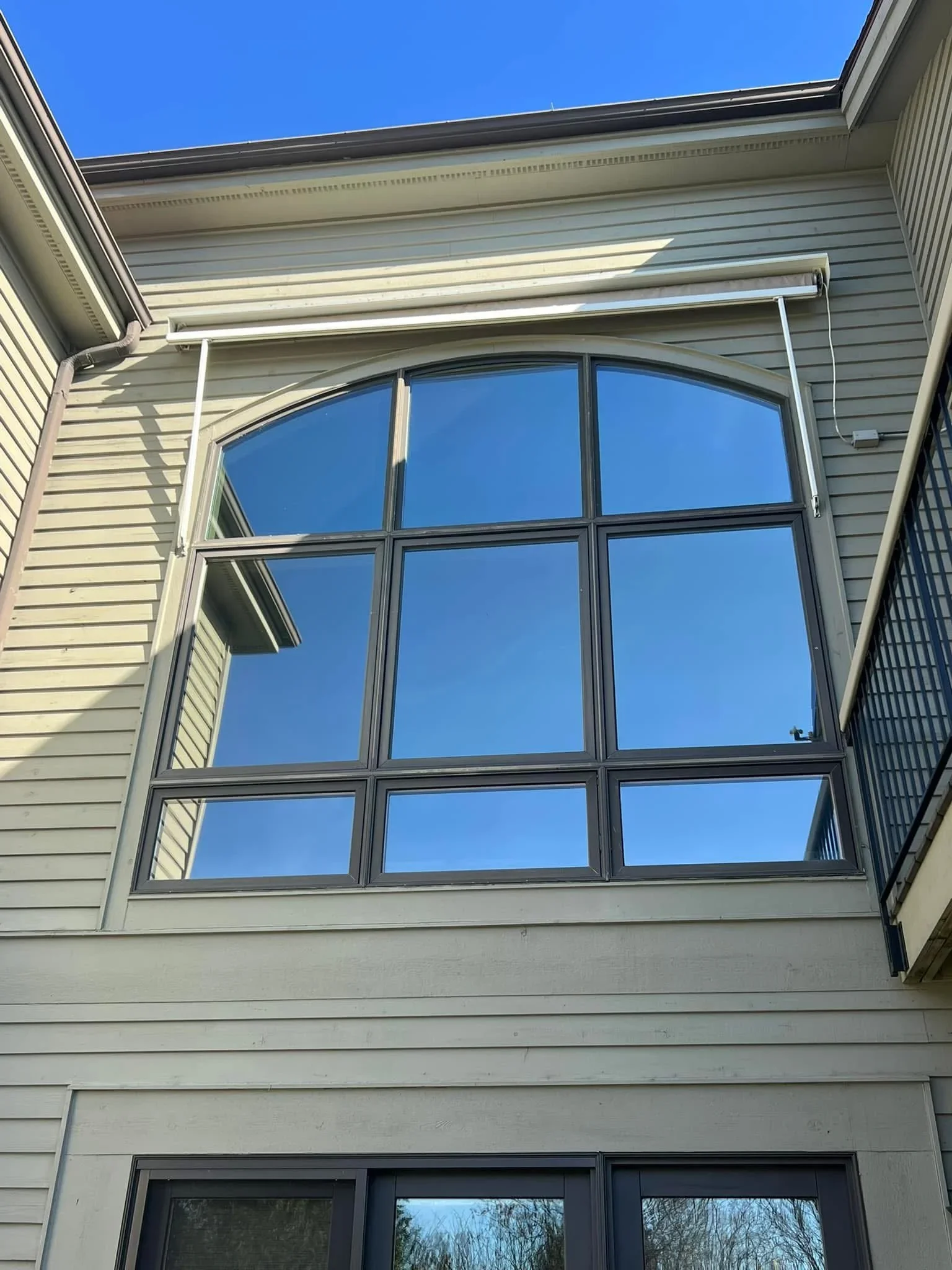9-pane residential window with dark aluminum frame and grid pattern installed on vinyl siding