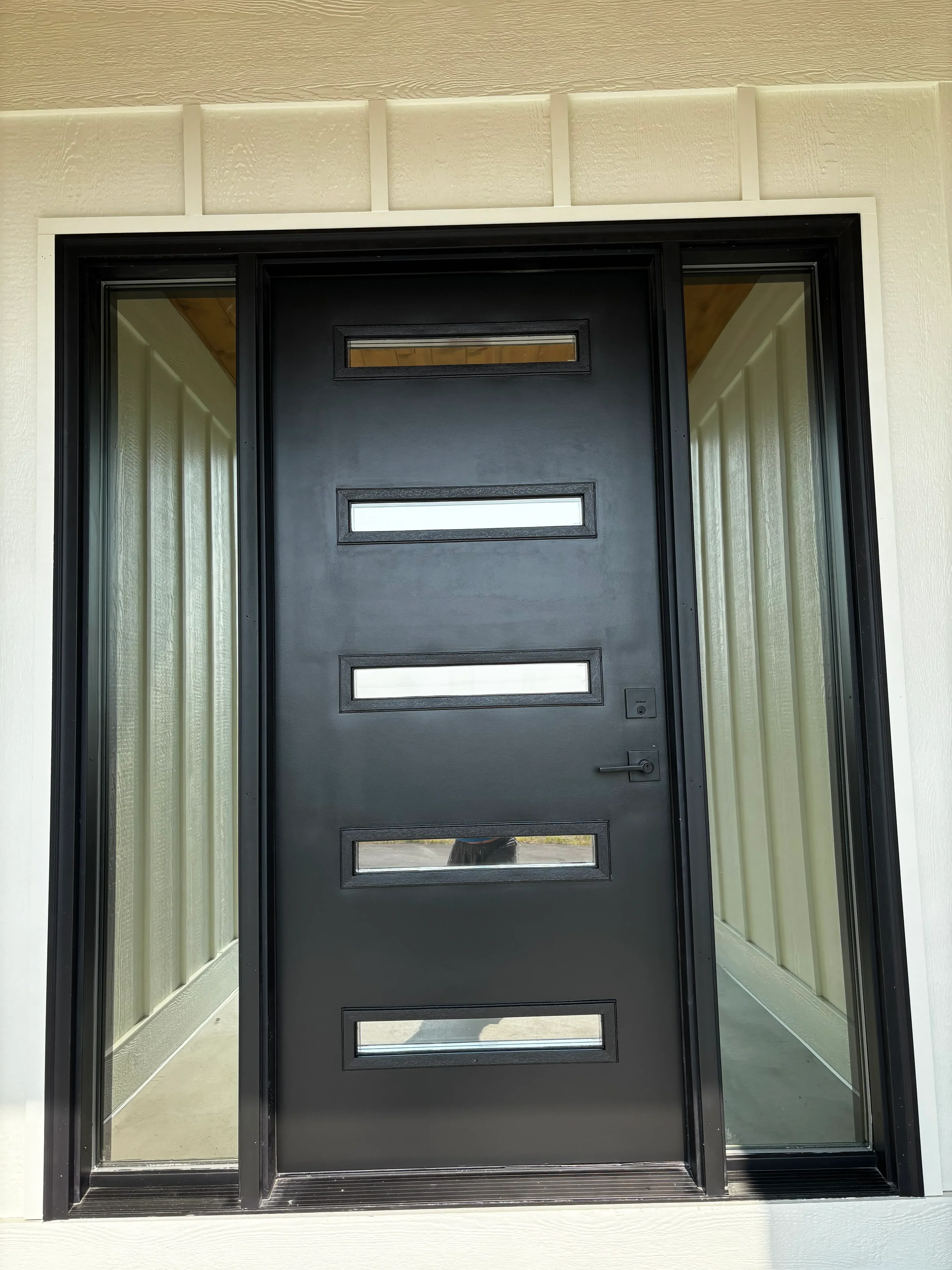 Black aluminum garage door with five vertical tinted glass panels and transom windows
