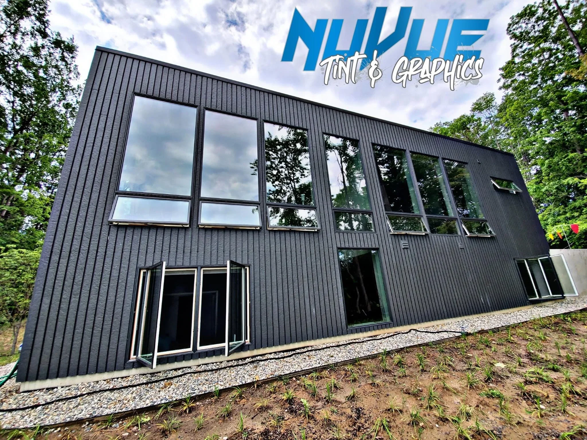 Black corrugated metal building with tinted windows and glass doors, modern architectural design